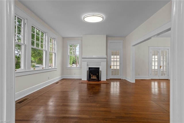 unfurnished living room with french doors, a fireplace, and wood-type flooring