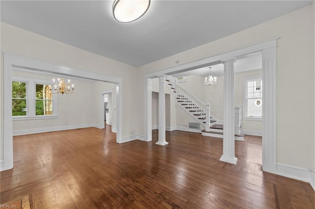 foyer entrance with dark wood-type flooring, an inviting chandelier, and decorative columns