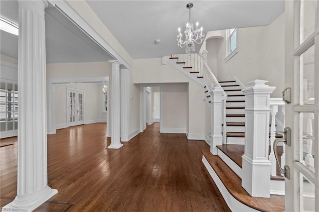 foyer with plenty of natural light, dark hardwood / wood-style flooring, an inviting chandelier, and ornate columns