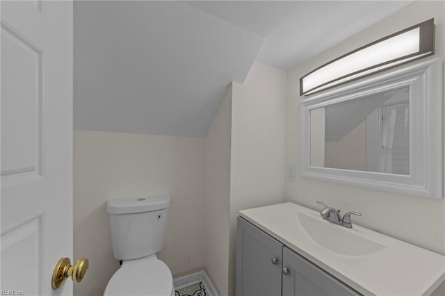 bathroom with vanity with extensive cabinet space, toilet, and lofted ceiling