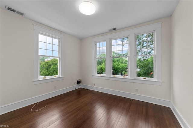 unfurnished room featuring dark hardwood / wood-style floors and a healthy amount of sunlight