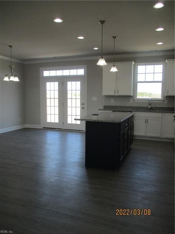 kitchen featuring light stone countertops, dark hardwood / wood-style floors, pendant lighting, and white cabinets