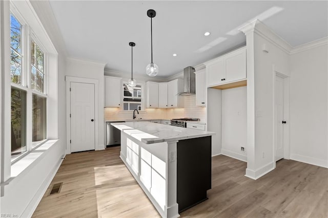 kitchen featuring a center island, light stone countertops, stainless steel appliances, white cabinets, and wall chimney exhaust hood