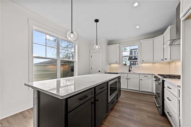 kitchen featuring pendant lighting, appliances with stainless steel finishes, a kitchen island, white cabinetry, and sink