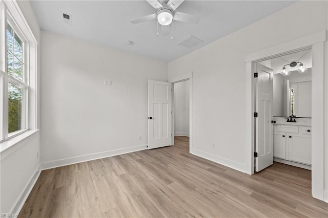 unfurnished bedroom with ceiling fan, ensuite bath, multiple windows, and light hardwood / wood-style flooring