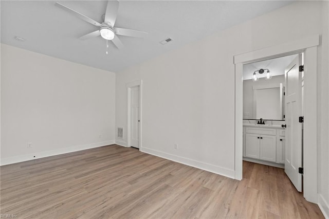 unfurnished bedroom with ensuite bath, light wood-type flooring, sink, and ceiling fan