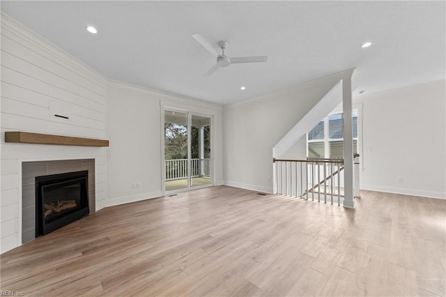 unfurnished living room with ceiling fan, light wood-type flooring, a tile fireplace, and ornamental molding