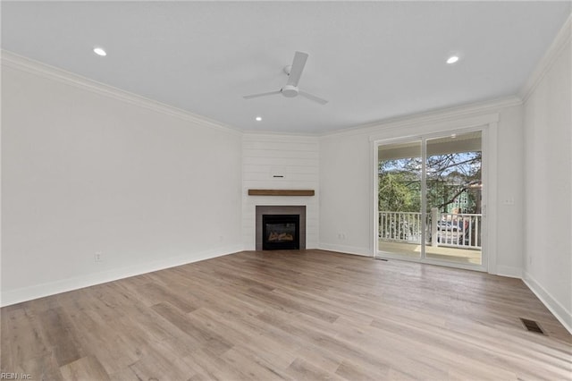 unfurnished living room featuring ceiling fan, a large fireplace, ornamental molding, and light hardwood / wood-style flooring