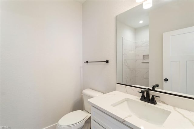 bathroom with toilet, vanity, and a tile shower