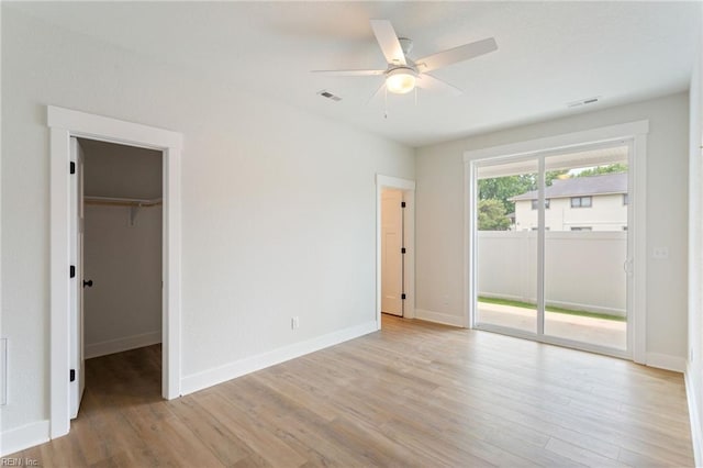 unfurnished bedroom with ceiling fan, light hardwood / wood-style floors, access to outside, a spacious closet, and a closet