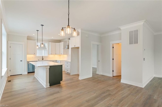 kitchen featuring pendant lighting, white cabinets, a center island, ornamental molding, and light wood-type flooring