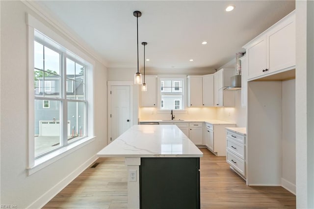 kitchen with light wood-type flooring, pendant lighting, a kitchen island, crown molding, and white cabinets