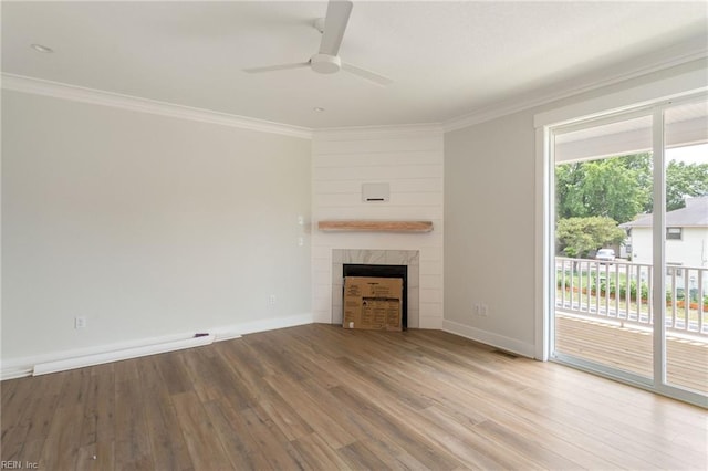 unfurnished living room featuring hardwood / wood-style flooring, ceiling fan, crown molding, and a tiled fireplace