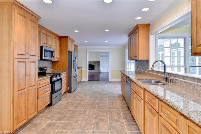 kitchen featuring crown molding, sink, light stone countertops, appliances with stainless steel finishes, and tasteful backsplash