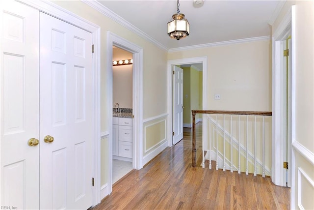 hall with crown molding, sink, and light wood-type flooring