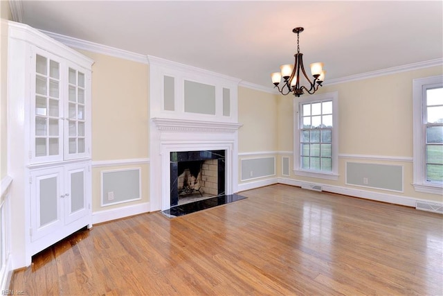 unfurnished living room with light hardwood / wood-style flooring, a high end fireplace, a notable chandelier, and ornamental molding