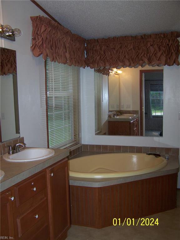 34026 Doctors Rd, Newsoms, VA 23874 - bathroom featuring vanity, a textured ceiling, and a bath