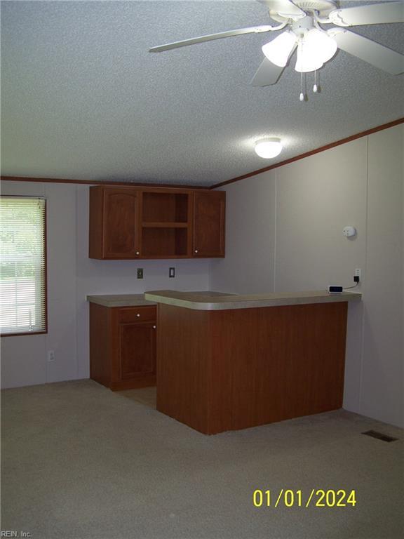 34026 Doctors Rd, Newsoms, VA 23874 - kitchen with brown cabinetry, ornamental molding, a textured ceiling, visible vents, and ceiling fan