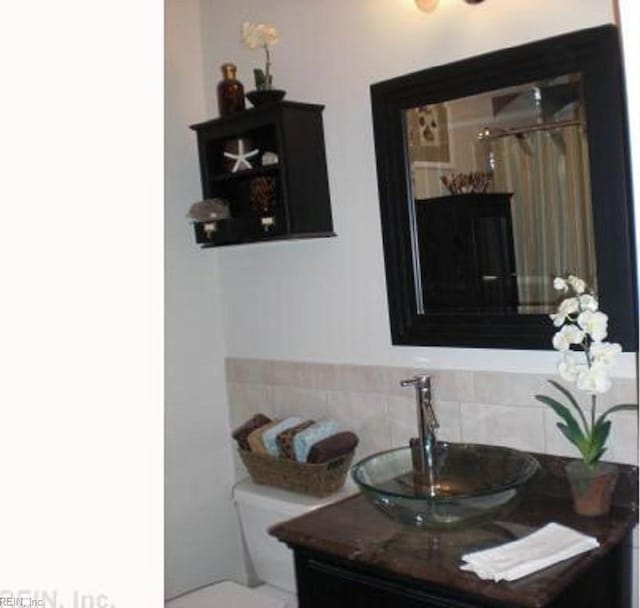 bathroom with backsplash, vanity, and toilet