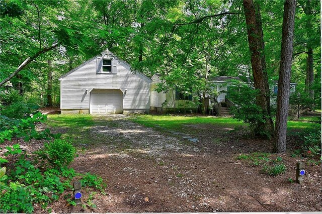 exterior space with a detached garage and dirt driveway