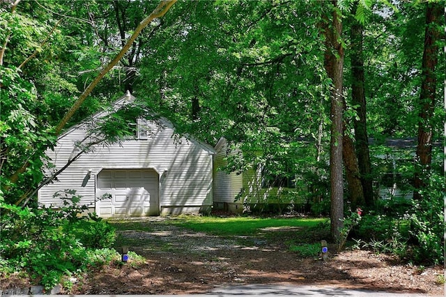 view of property exterior with a garage, an outbuilding, and driveway