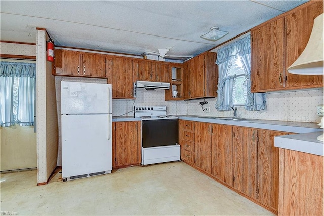 kitchen featuring light floors, white appliances, a sink, and brown cabinets