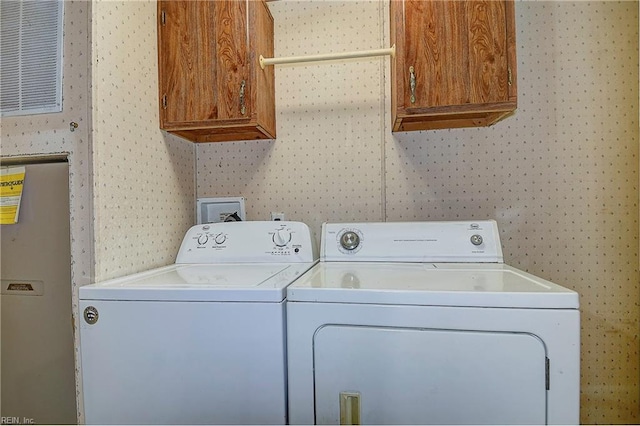 washroom with wallpapered walls, separate washer and dryer, and cabinet space