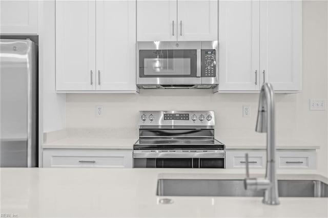 kitchen with stainless steel appliances, white cabinetry, and sink