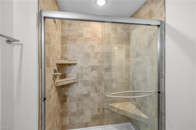 bathroom featuring a shower with door and a textured ceiling