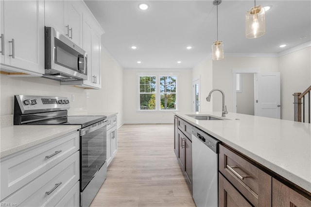 kitchen featuring appliances with stainless steel finishes, decorative light fixtures, sink, white cabinets, and light hardwood / wood-style floors