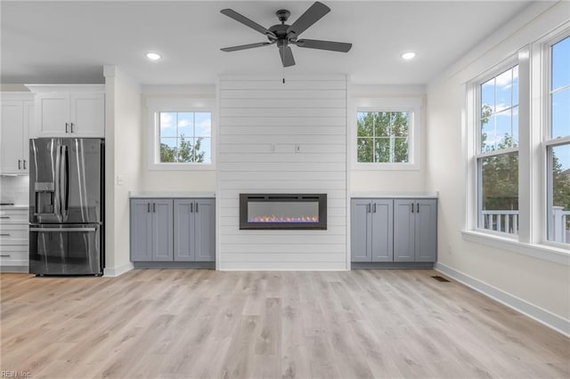 unfurnished living room with light hardwood / wood-style floors, a large fireplace, and ceiling fan