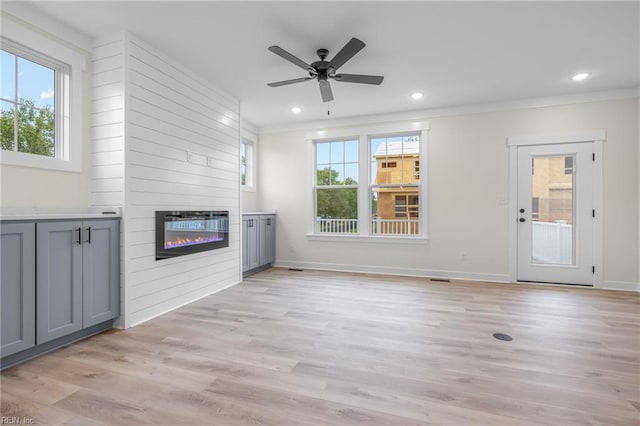 unfurnished living room featuring crown molding, a fireplace, and light hardwood / wood-style floors