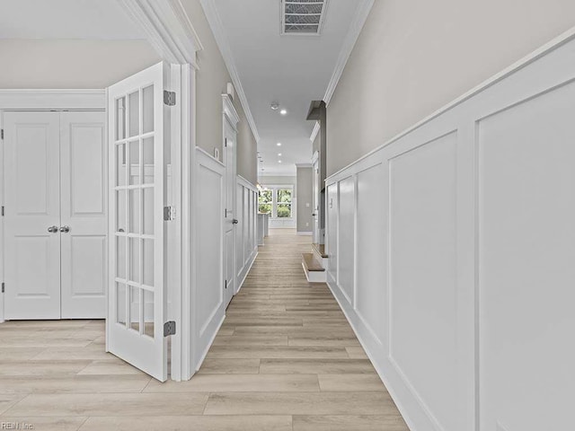 hallway with light wood-type flooring and crown molding