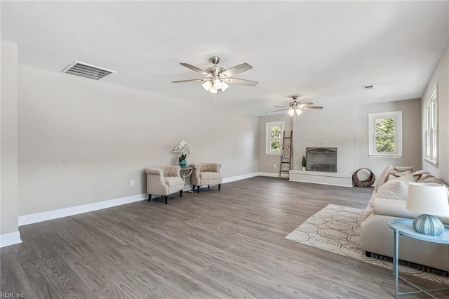 unfurnished living room featuring wood-type flooring, a large fireplace, and ceiling fan