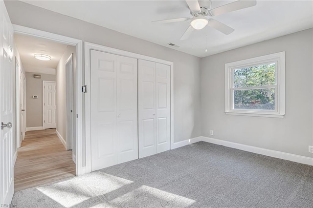 unfurnished bedroom with ceiling fan, a closet, and light carpet