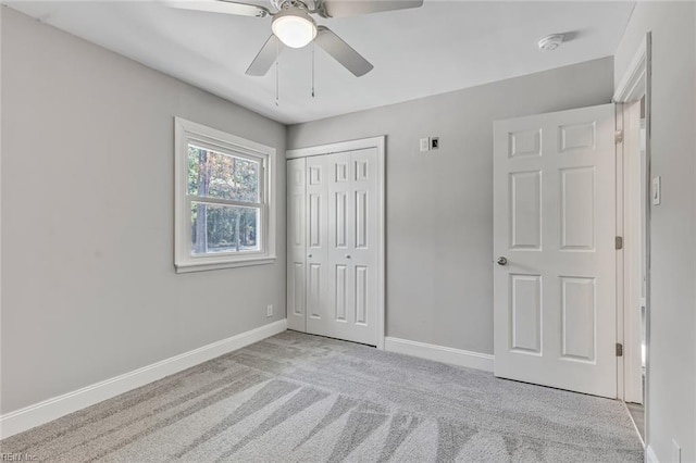 unfurnished bedroom featuring ceiling fan, a closet, and light carpet