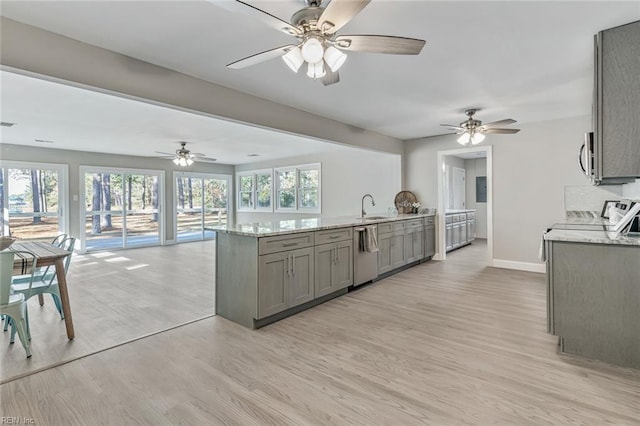 kitchen featuring light stone counters, gray cabinetry, stainless steel appliances, sink, and light hardwood / wood-style floors