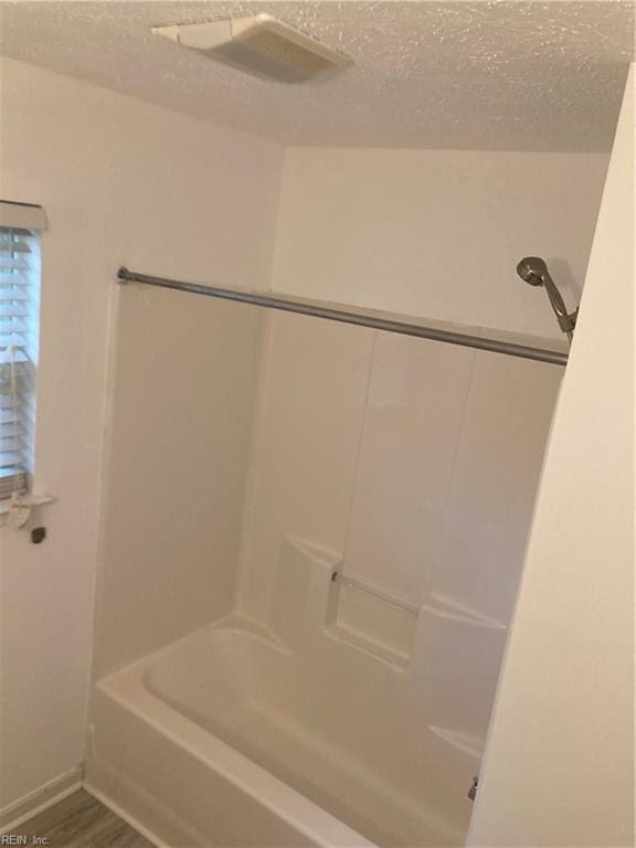 bathroom with shower / bath combination, a textured ceiling, and hardwood / wood-style flooring