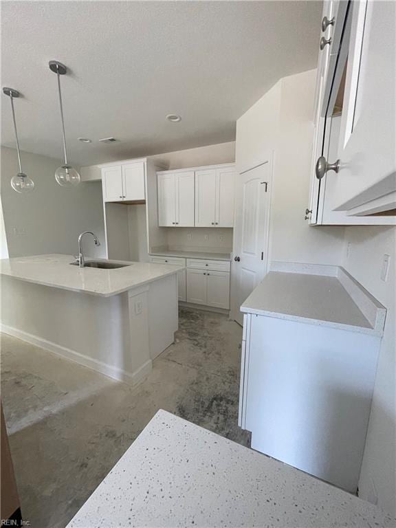 kitchen featuring sink, white cabinets, pendant lighting, and a kitchen island