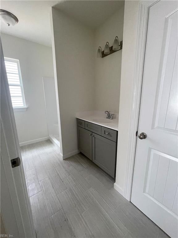 bathroom with hardwood / wood-style flooring, vanity, and walk in shower