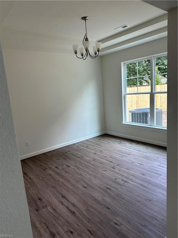 empty room featuring dark wood-type flooring and an inviting chandelier