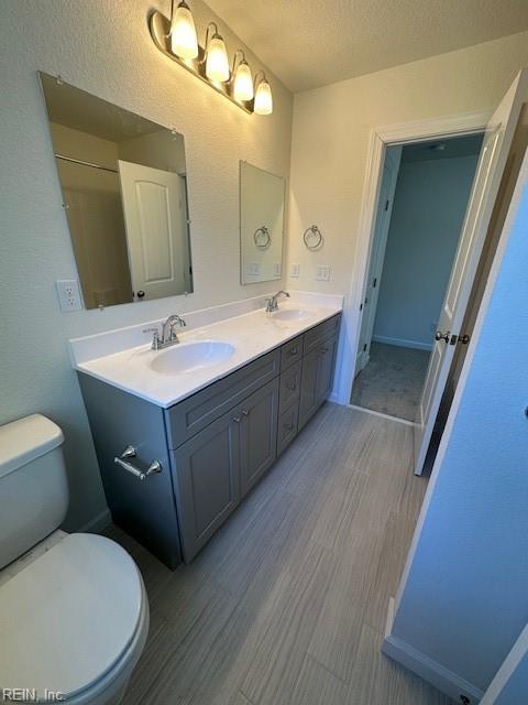 bathroom with hardwood / wood-style flooring, vanity, toilet, and a textured ceiling