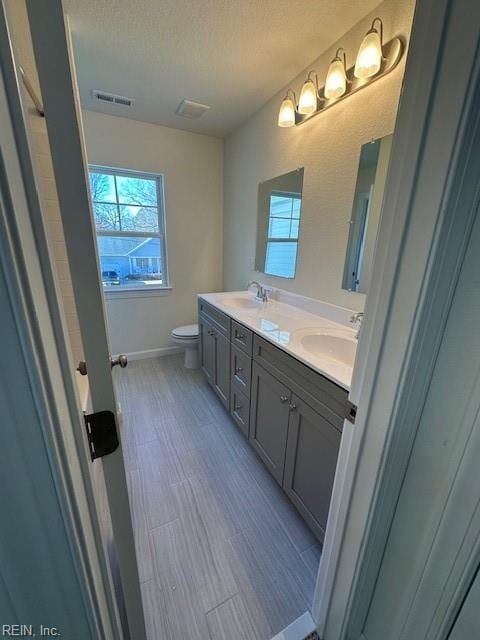 bathroom featuring vanity, toilet, and a textured ceiling