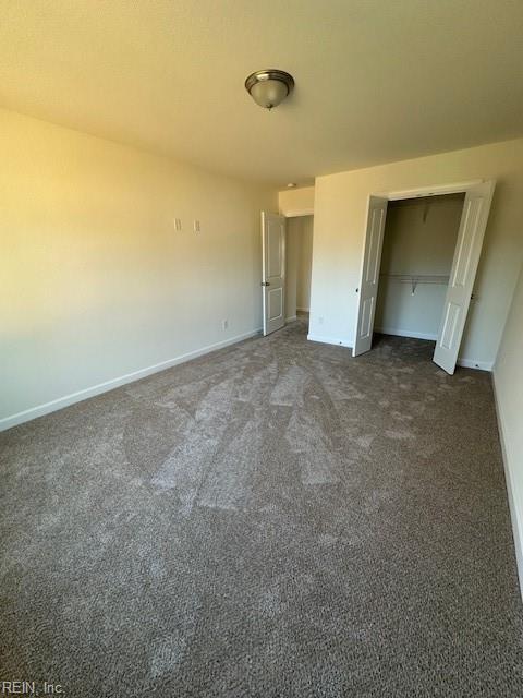 unfurnished bedroom featuring a closet and dark colored carpet