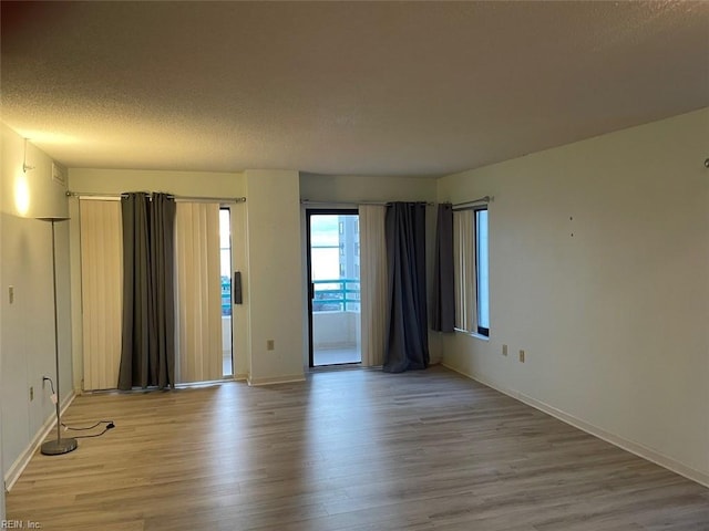 unfurnished room with a textured ceiling and light hardwood / wood-style flooring