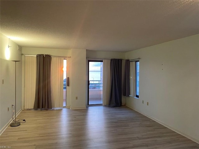 unfurnished room featuring wood-type flooring and a textured ceiling