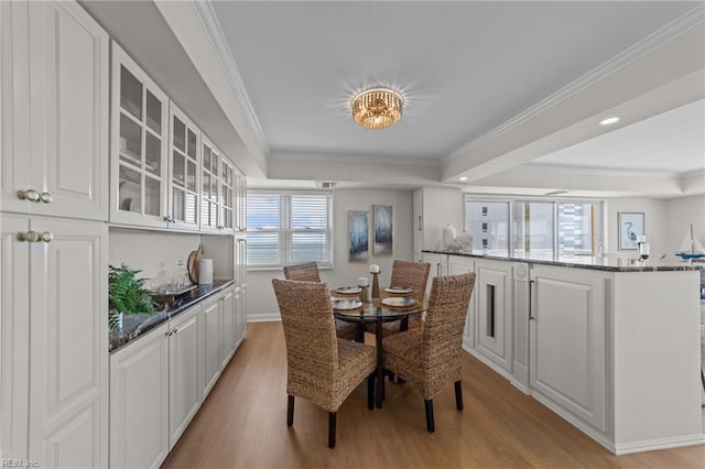 dining space with a healthy amount of sunlight, light wood-type flooring, and ornamental molding