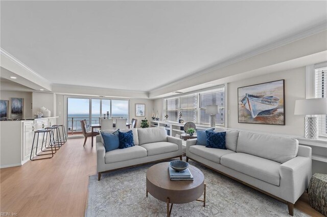 living room featuring ornamental molding, a water view, and wood-type flooring