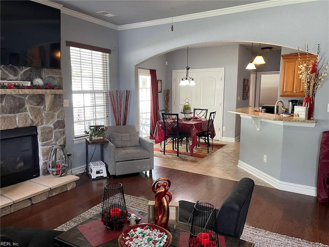 living room featuring sink, a fireplace, light tile patterned floors, and crown molding