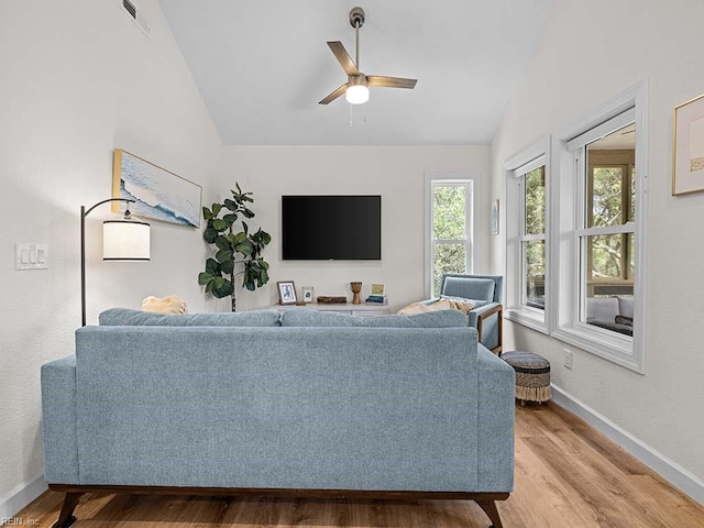 living room with ceiling fan, vaulted ceiling, and light wood-type flooring